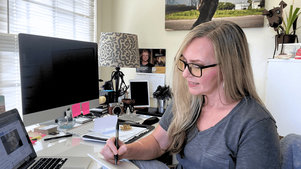 Sandy Adams writing at her desk while discussing AI, leadership and the importance of human thinking