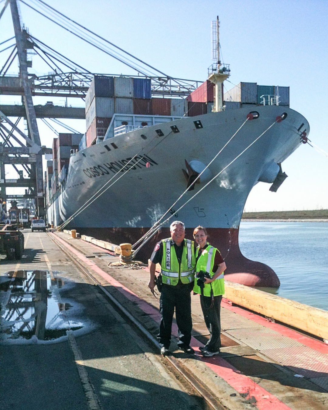 Sandy Adams standing with a port police officer beside a container ship at the Port of Houston